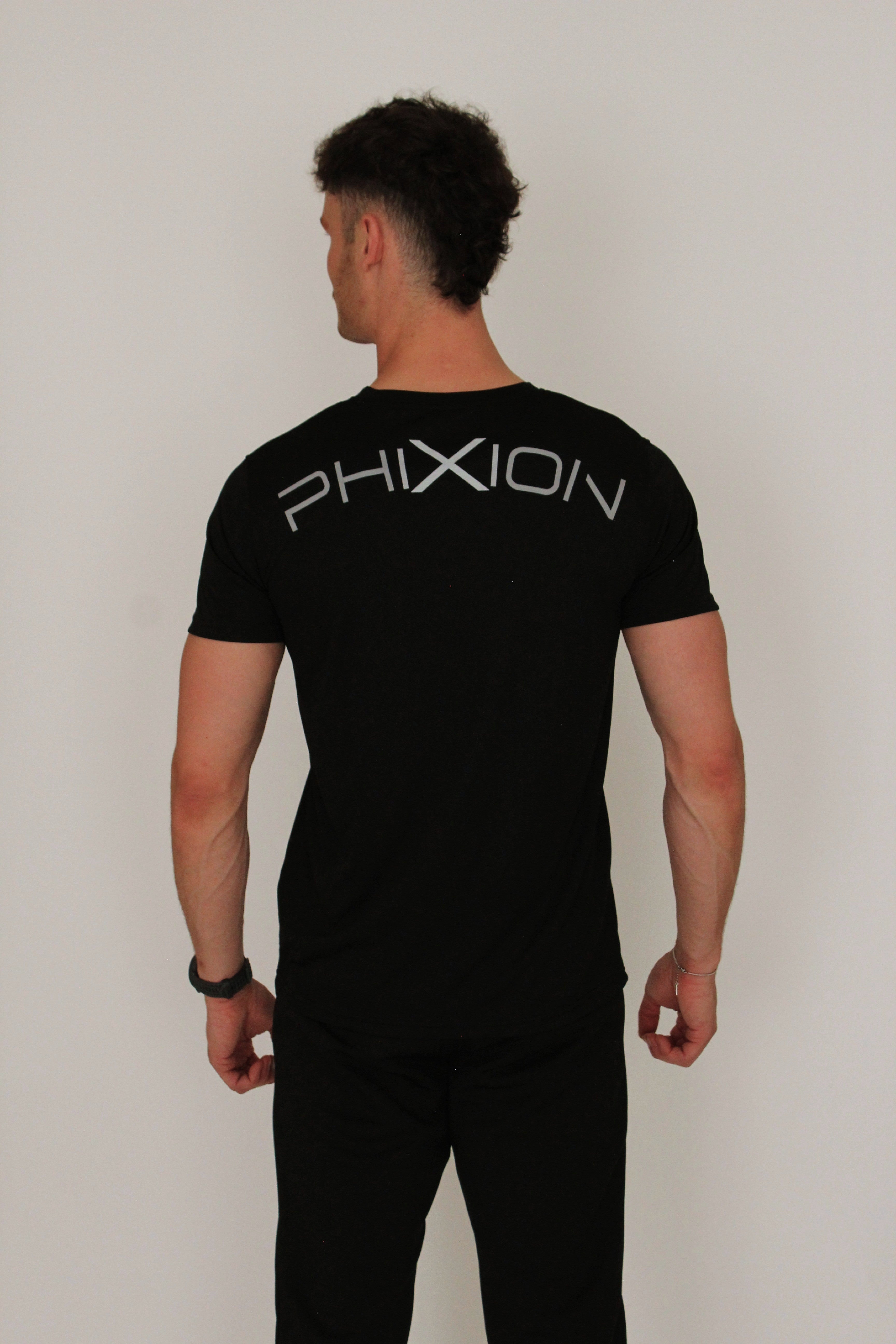 Back view of model wearing Phixion Active T-Shirt. Features bold curved Phixion branding across the upper back.