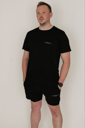 Model wearing Phixion Twin Skin Shorts in black against a white background. Athletic fit showcases the performance design.