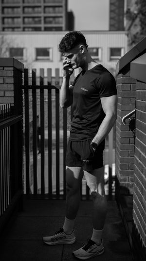 Phixion Twin Skin Shorts styled in an urban setting. Model standing outdoors on the phone, showing comfort and versatility.